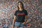 Person wearing a black t-shirt with 'Canasta' text in red, standing against a wall of playing cards.