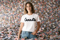Woman wearing a white t-shirt with 'Canasta' text in front of a wall covered with playing cards.