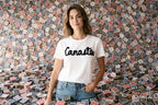 Woman wearing a white t-shirt with 'Canasta' text in front of a wall covered with playing cards.