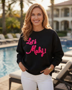 Woman wearing a black sweatshirt with 'Let's Mahj!' in pink text by a poolside.