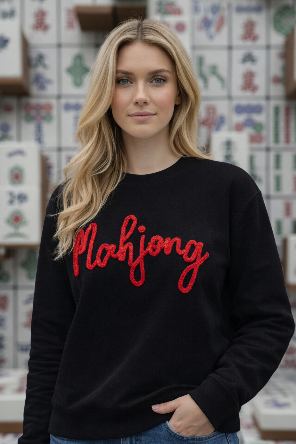 Woman wearing a black sweater with 'Mahjong' in red text, standing in front of colorful tiles.