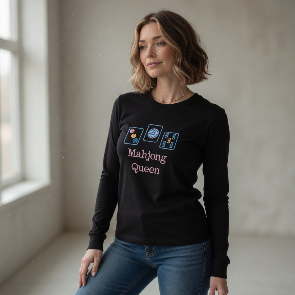 Woman wearing a black long-sleeve shirt with 'Mahjong Queen' text and symbols in a room with natural light.