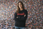 Person wearing a black sweatshirt with 'Canasto' text standing in front of a wall with small colorful flags.
