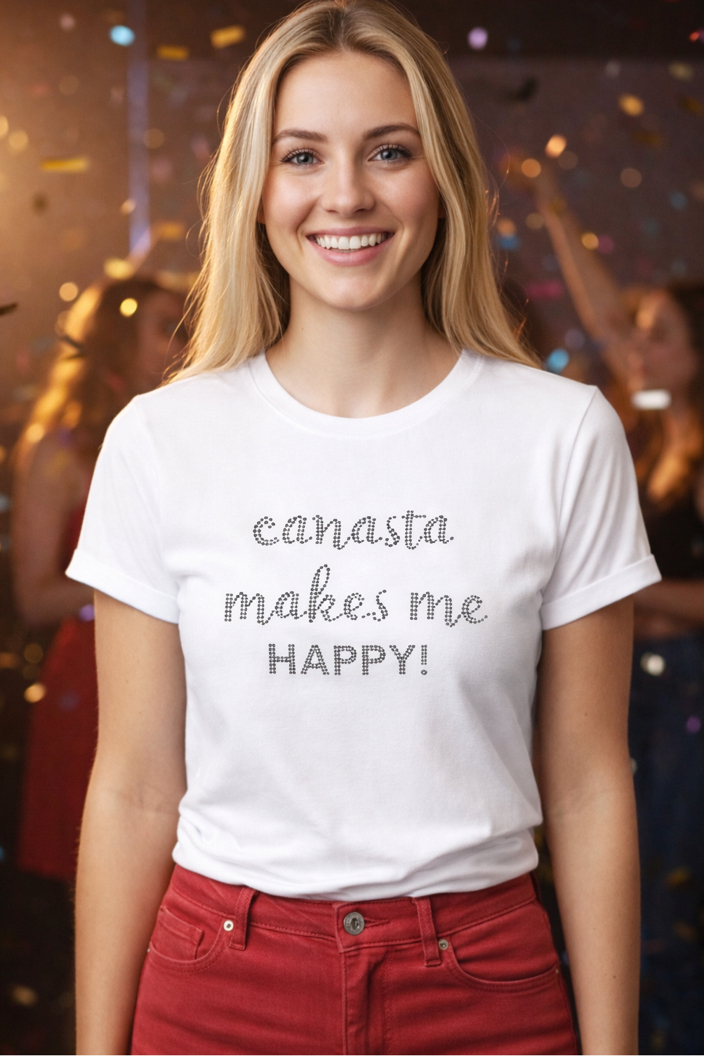 Woman wearing a white t-shirt with 'canasta makes me HAPPY!' text, standing in a festive setting.