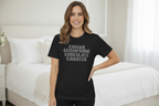 Woman wearing a black t-shirt with text in a bedroom setting