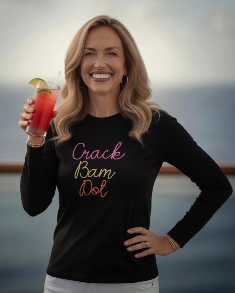Woman holding a drink with a scenic background, she is wearing a black long sleeve with crack bam dot design for mahjong tops