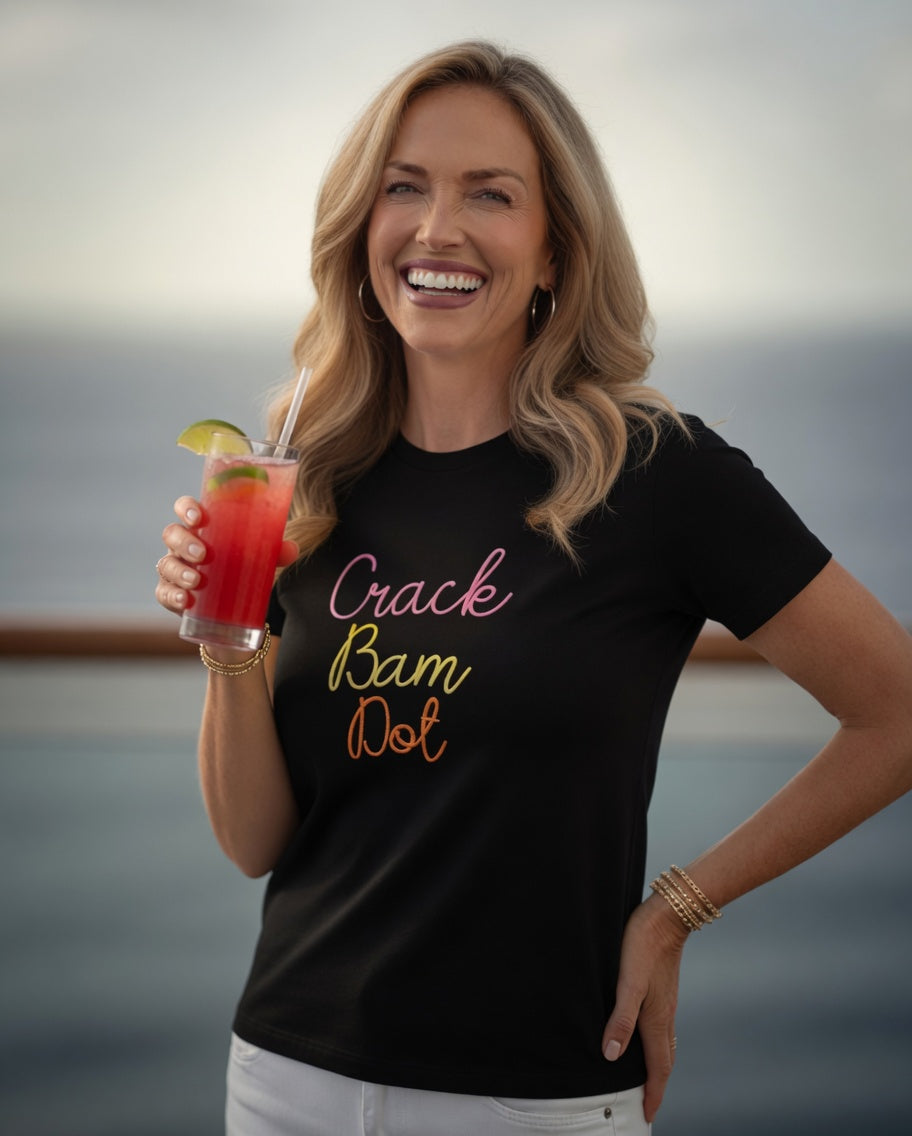Woman wearing short sleeve tee in black with crack bam dot design, standing and holding a mocktail.