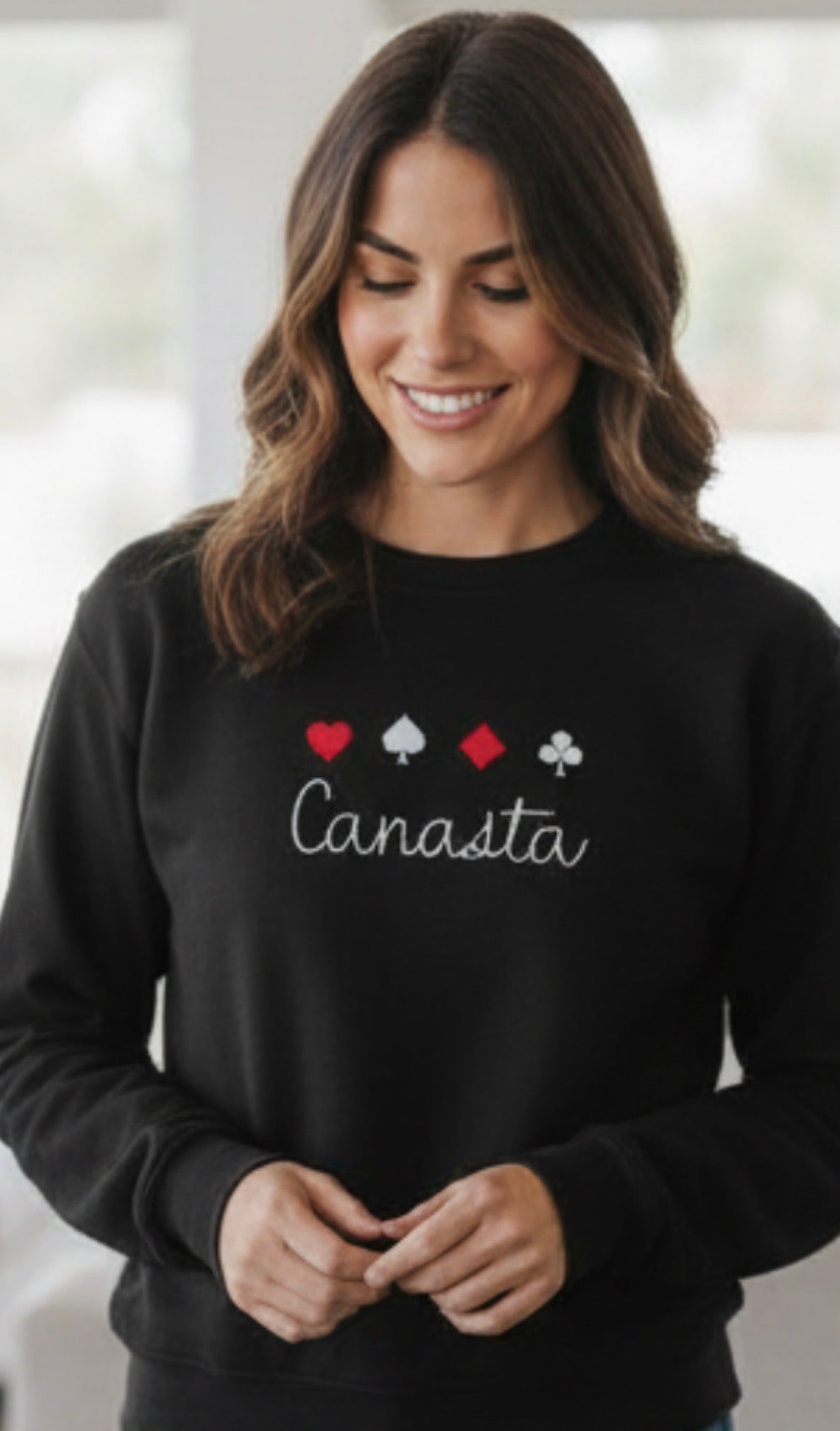 Woman wearing a black sweater with 'Canasta' and card suit symbols.