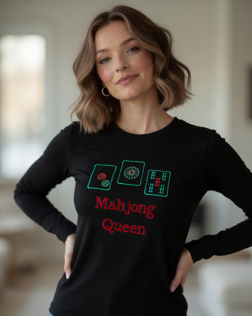 Woman wearing black long sleeve tee with embroided Mahjong Queen design posing inside the interior room setting