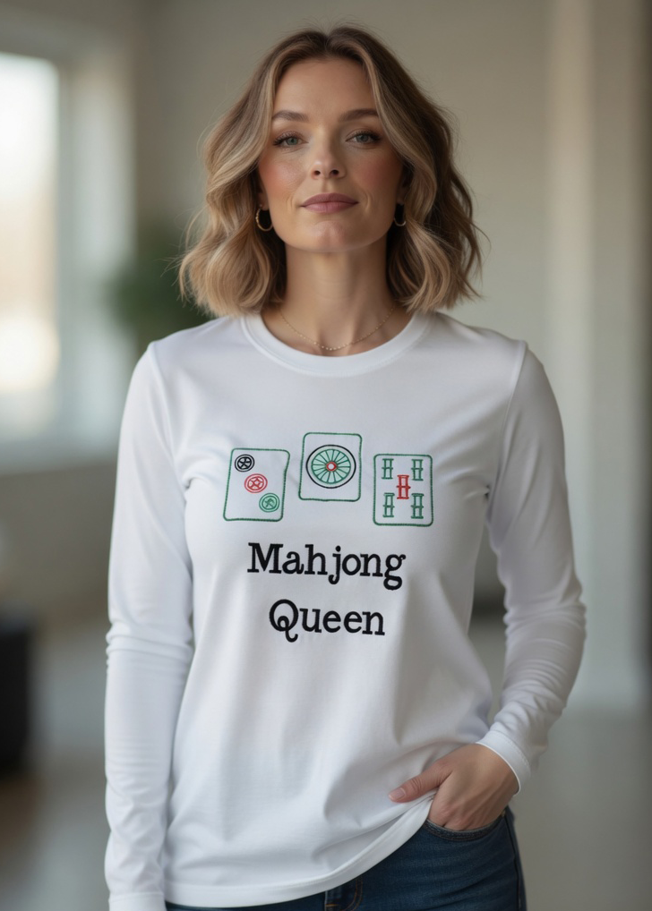 Woman wearing black long sleeve tee with embroided Mahjong Queen design posing inside the interior room setting