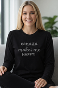 Woman wearing a black shirt with 'canasta makes me HAPPY!' text, sitting on a couch.